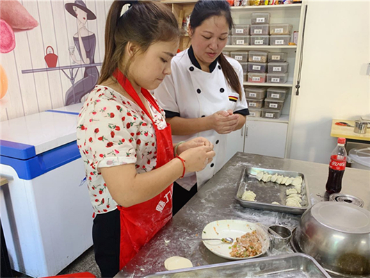 魅力小吃培訓(xùn)學(xué)校現(xiàn)場(chǎng)教女學(xué)員餃子制作